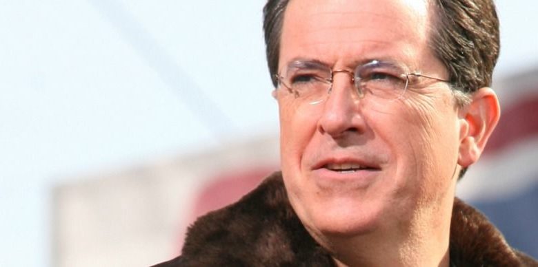 Stephen Colbert wearing glasses and smiling at the camera