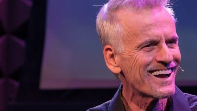 Rob Paulsen wearing a purple shirt and smiling at the camera